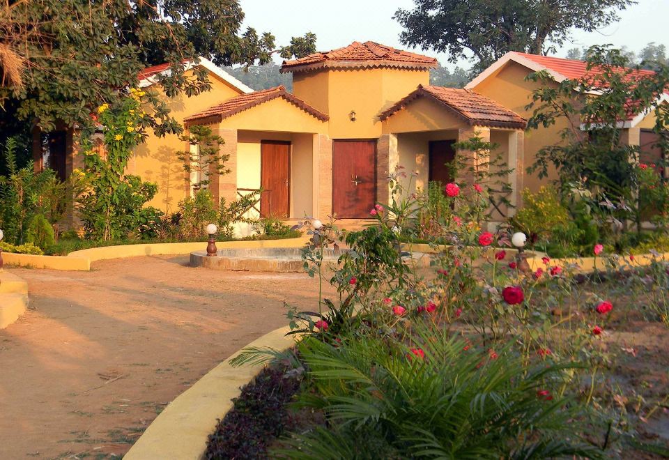 a house with a red roof and orange shutters is surrounded by a garden of flowers at Wildflower Resort