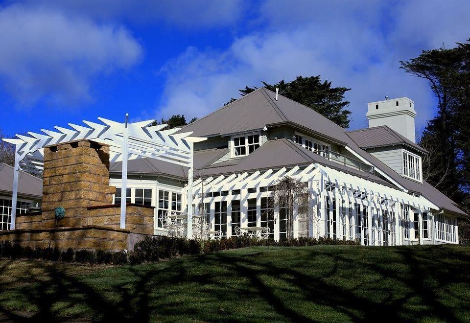 a large white house with a brick chimney on top of it , surrounded by a grassy field at Parklands Country Gardens & Lodges Blue Mountains