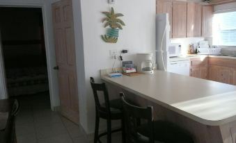 a kitchen with a white countertop , black chairs , and a microwave on the wall , next to a living room at Cottage Cut Villas