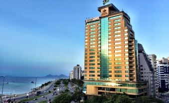 a tall building with a green flag on top is surrounded by a cityscape and water at Majestic Palace Hotel