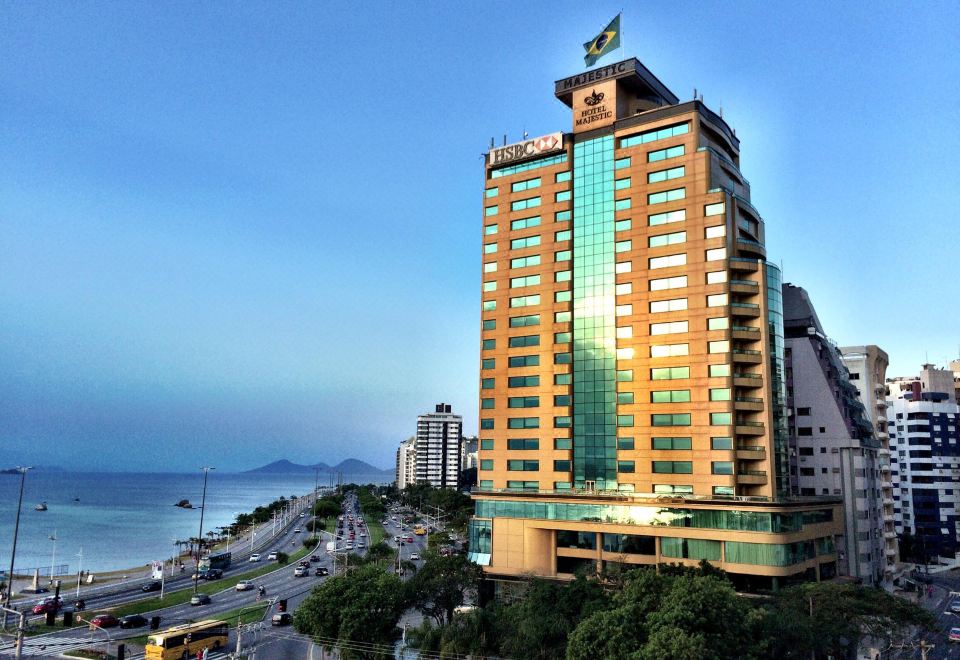 a tall building with a green flag on top is surrounded by a cityscape and water at Majestic Palace Hotel