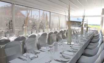 a long dining table is set with white linens , silverware , and glasses for a formal event at Sage Hotel Wollongong