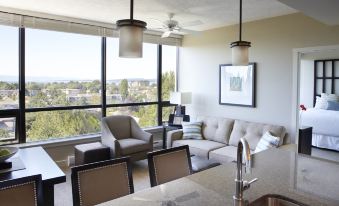 a living room with a couch , chairs , and dining table in front of a large window at Oswego Hotel