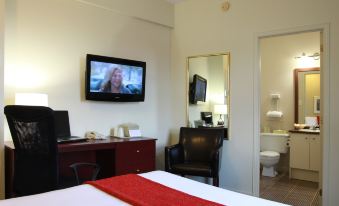 a modern hotel room with a tv , desk , and bed , as well as a view of a bathroom through the window at Hotel du Nord