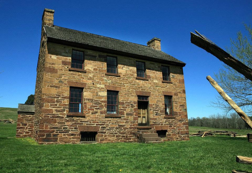 a large stone house with a green lawn and a clear blue sky in the background at Courtyard Manassas Battlefield Park