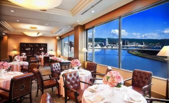 a restaurant with large windows overlooking a body of water , creating a serene and romantic atmosphere at Numazu River Side Hotel