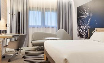 a modern bedroom with a large bed , desk , and window , decorated with white curtains and black and white striped carpet at Novotel Tours Centre Gare