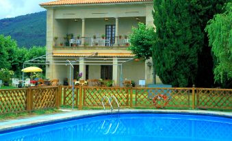 a large house with a swimming pool in front of it , surrounded by trees and grass at Parador de Verin