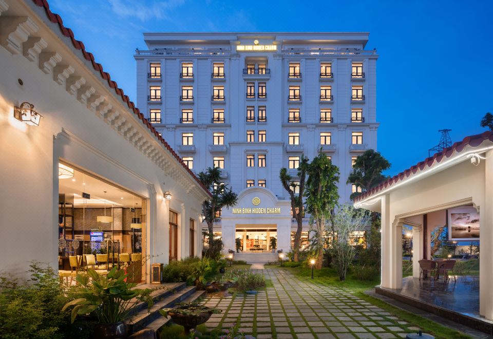"a large white building with many windows and a sign that reads "" hotel jingjiang ."" the building appears to be a hotel or" at Ninh Binh Hidden Charm Hotel & Resort