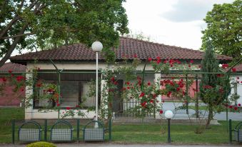 a house with a red tile roof and red flowers in front of it , surrounded by a fence at Hotel Bellevue