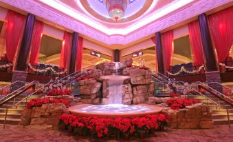 a large indoor fountain with red flowers and a waterfall in the center , surrounded by a room filled with chandeliers and red flowers at Mount Airy Casino Resort - Adults Only 21 Plus