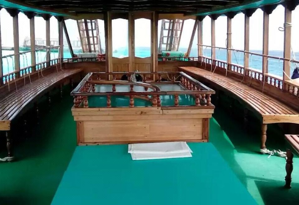 a wooden boat is floating on a green river , with the interior of the boat visible through a large window at Paradise Lagoon