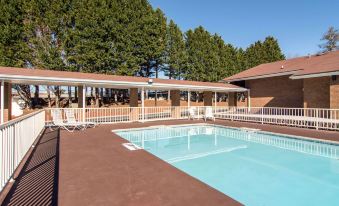 an outdoor pool surrounded by a brick building , with lounge chairs and umbrellas placed around the pool area at Quality Inn