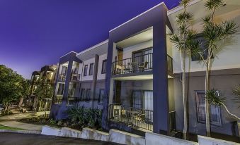a modern apartment building with multiple balconies , surrounded by trees and lit up at night at Quest Ipswich