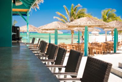 a row of black and white chairs lined up in front of a beach bar at Wyndham Reef Resort Grand Cayman