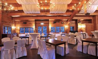 a large , well - decorated dining room with white tables and chairs , draped in white tablecloths and surrounded by windows at Fletcher Hotel Restaurant de Wipselberg-Veluwe