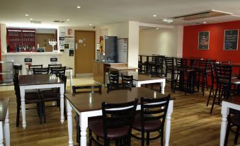 a large dining area with several tables and chairs , as well as a kitchen in the background at 247Hotel.Com