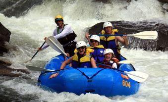 a group of five people wearing helmets and life jackets are riding on a blue inflatable raft through rough rapids at Lake Rabun Hotel