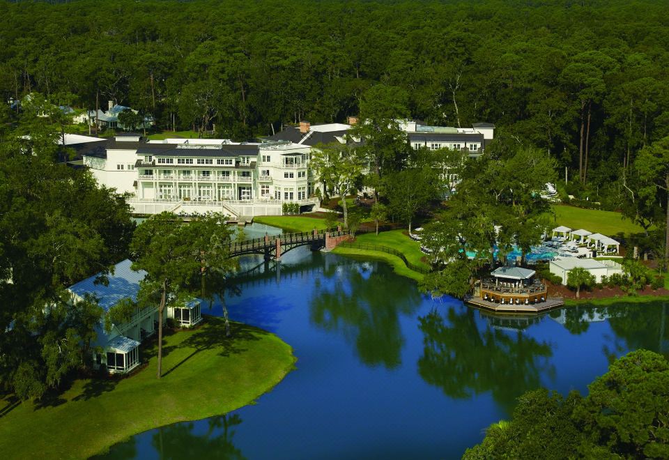 a large white building surrounded by trees , with a body of water in front of it at Montage Palmetto Bluff