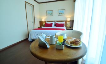 a hotel room with a bed , table , and breakfast items , including a plate of croissants and orange juice at Oxford Hotel