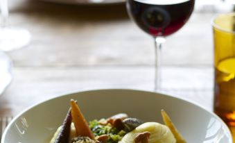 a plate of food is placed on a wooden table next to a glass of wine at The Welldiggers Arms