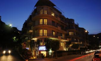 a modern , three - story building with balconies and trees , lit up at night , with cars driving on the street at Hotel Majestic