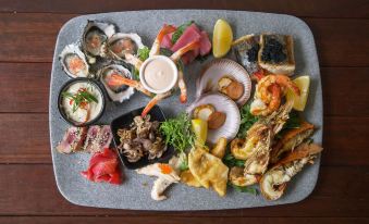 a large platter filled with a variety of seafood , including oysters , shrimp , and fish , on a dining table at The Sebel Brisbane Margate Beach