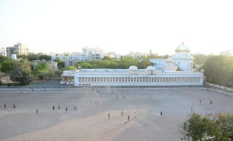 a large white building with a green dome is surrounded by a courtyard filled with people at Lime Tree Hotel