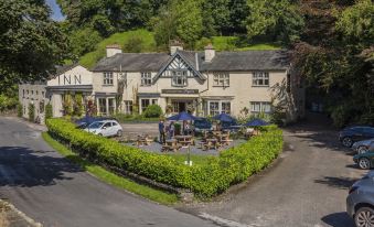 "a brick building with a sign that says "" inn "" is surrounded by trees and has a car parked in front of it" at The Cuckoo Brow Inn