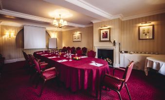 a large conference room with a long table , chairs , and a fireplace , decorated in a traditional style at Small Luxury Hotels of the World - the Mitre Hampton Court