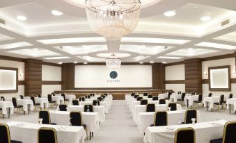 a large , empty conference room with white walls and a chandelier , set up for a meeting or event at Paloma Pasha