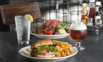 a dining table with two plates of food , one containing a burger and fries , and the other featuring a plate of salad at Lake Bomoseen Lodge