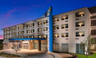 an exterior view of a hotel with a large sign above the entrance , illuminated at night at GLo Best Western DeSoto Dallas