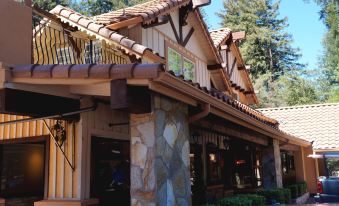 a brown wooden building with a red tile roof and brown stone pillars in front of it at The Historic Brookdale Lodge, Santa Cruz Mountains