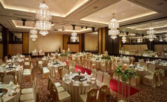 a large , elegant banquet hall with multiple tables set for a formal event , including white tablecloths , gold chairs , and red car at PARKROYAL Penang Resort