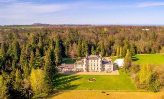 aerial view of a large , old mansion surrounded by trees and grass , located in a wooded area at Melville Castle Hotel
