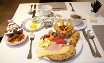 a dining table with a breakfast spread consisting of various food items , including eggs , bacon , and ham at Hotel Carlton