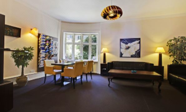 a well - lit living room with a couch , dining table , chairs , and a coffee table , creating a cozy atmosphere at Hotel Sct. Thomas
