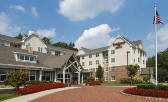 a large building with a red brick walkway in front of it , surrounded by trees and bushes at Residence Inn Philadelphia Langhorne