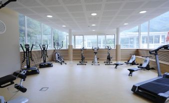 a large , well - equipped gym with various exercise equipment and a view of the outdoors through large windows at Hotel & Spa Radiana