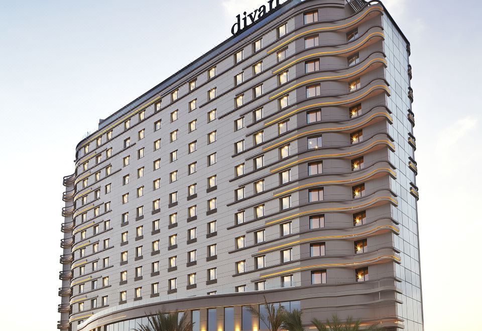 "a modern hotel building with its name "" black swan "" on top , surrounded by palm trees and other buildings" at Divan Mersin