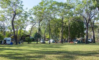 a group of people gathered in a park - like setting , surrounded by trees and a tent at Breeze Holiday Parks - Mary River