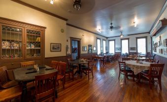 a large dining room with wooden floors , wooden tables , and chairs arranged for a group of people at Grand Victorian Inn