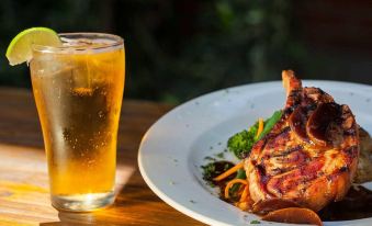 a white plate with a piece of meat on it , accompanied by a glass of beer at Prince of Wales Hotel