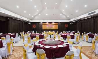 a well - decorated banquet hall with multiple round tables covered in white tablecloths and adorned with yellow ribbons at Diamond Park Inn Chiangrai & Resort