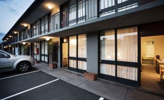 a building with multiple windows and a car parked in front , including one of the windows covered by a glass barrier at Nightcap at Matthew Flinders Hotel