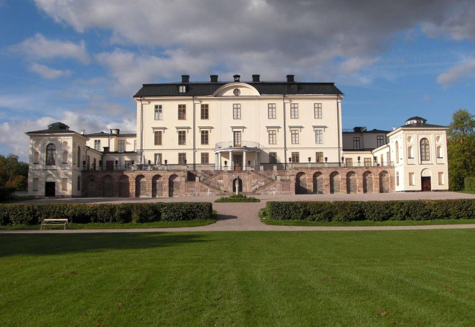 a large white building with a green lawn in front of it , surrounded by trees at Rosersbergs Slottshotell