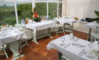 a restaurant with white tables and chairs , a vase of flowers , and a large window at Northumberland Cottage