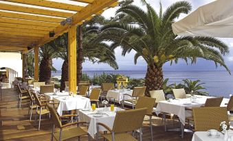 an outdoor dining area with several tables and chairs , providing a pleasant atmosphere for guests at Louis Ionian Sun