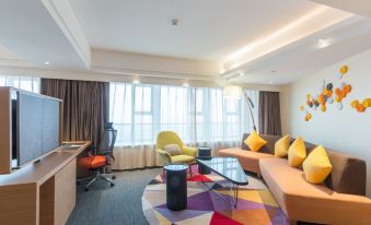 The living room, adorned with large windows, features a centrally placed couch and chair at Hampton by Hilton Ji'an